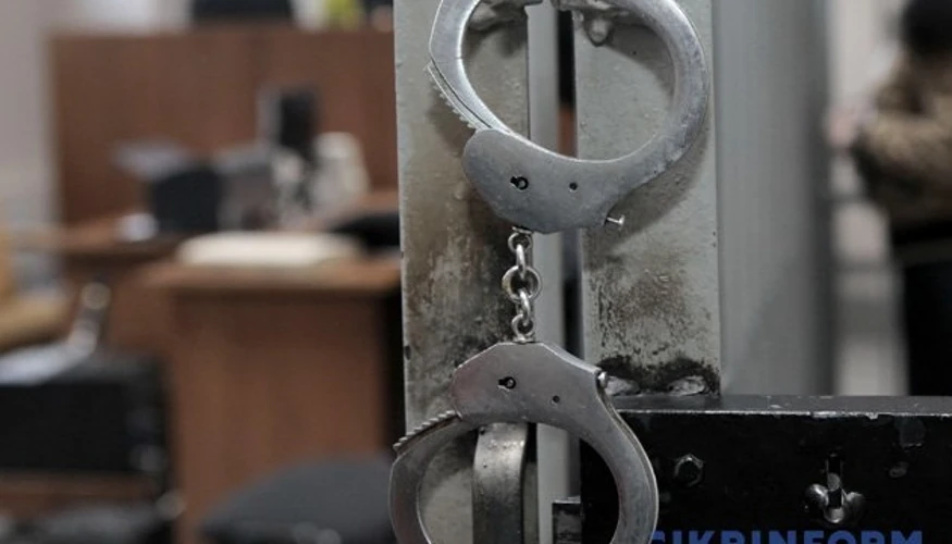 Заґратоване вікно на тлі силуетів фігурантів справи у Вроцлаві